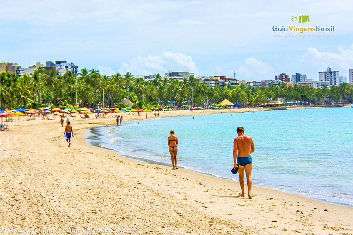 Imagem de turistas caminhando na Praia de Pajuçara, em Maceió, Alagoas, Brasil.
